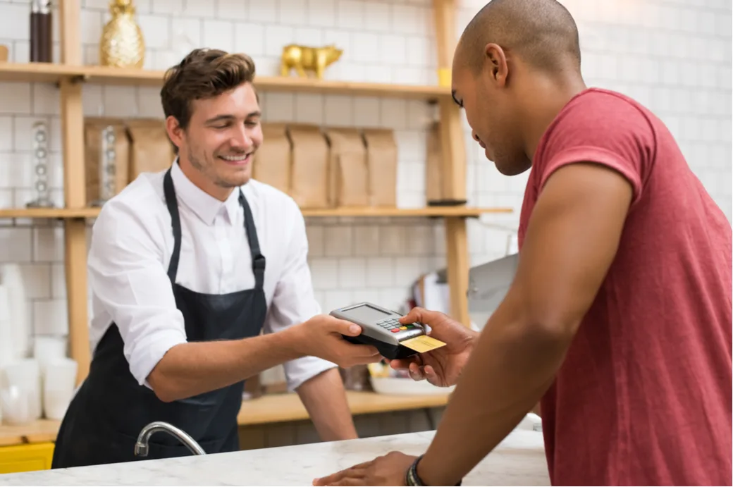 A merchant helping a customer pay at a café counter